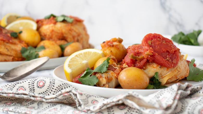 piri piri chicken with tomatoes, lemons, and potatoes on plate