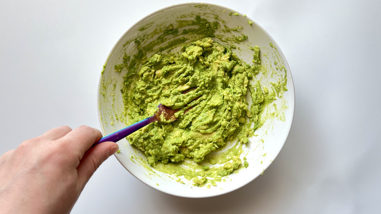 fork mashing avocado in bowl