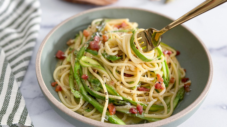 spaghetti carbonara with asparagus in bowl