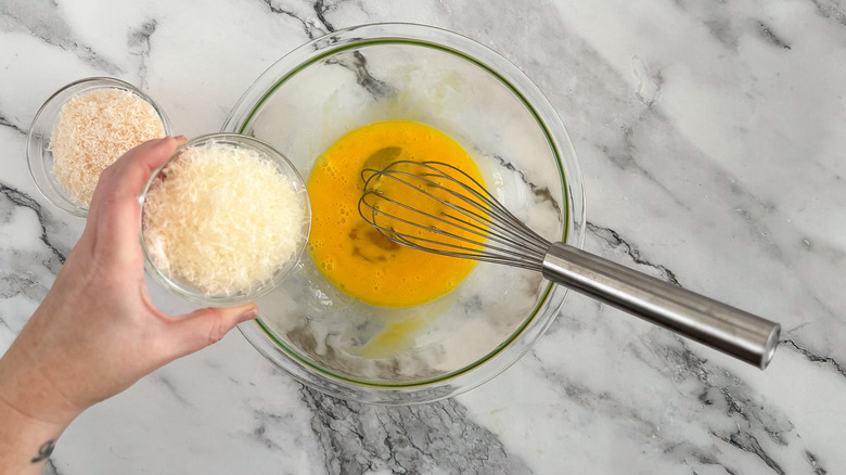 hand holding cheese over eggs