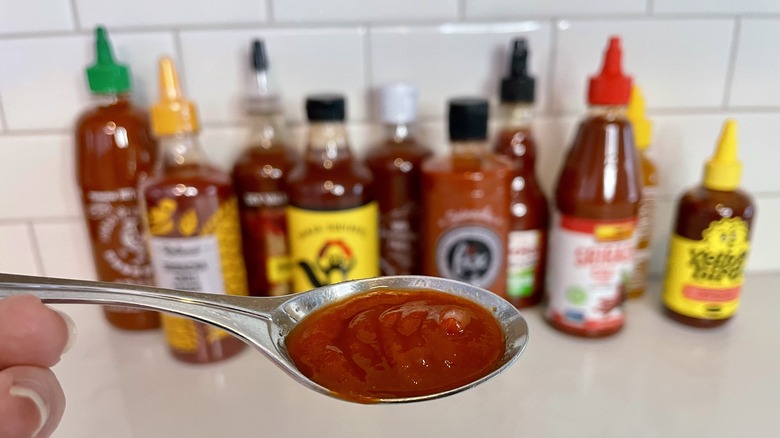 spoon of sriracha in front of bottles