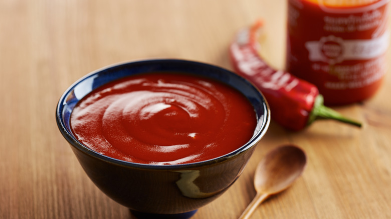 bowl of sriracha next to sriracha bottle