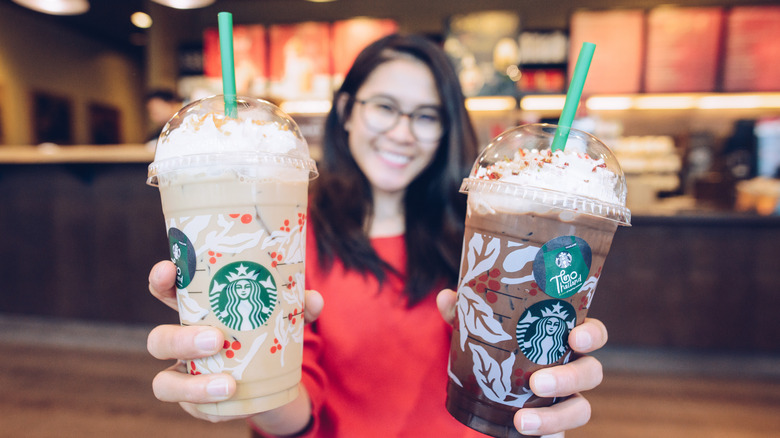 Woman holding two Starbucks holiday Frappuccinos 