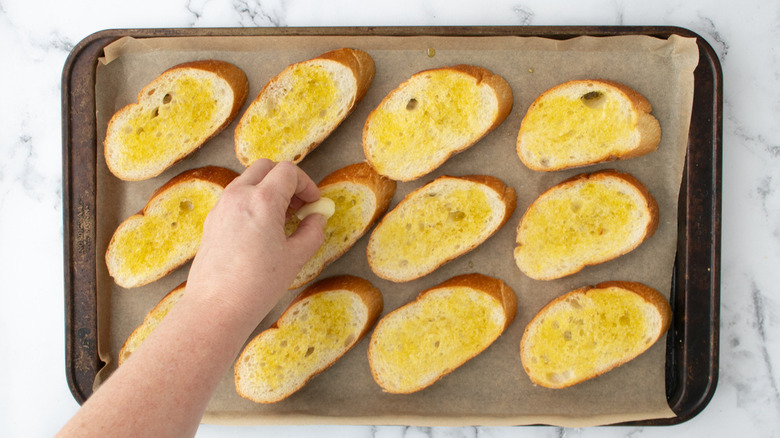 hand rubbing garlic on bread