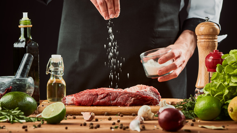 Man seasoning steak with salt