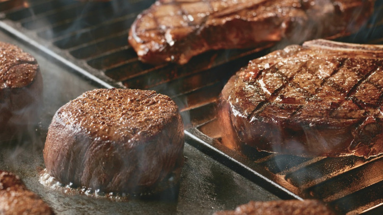 Assorted steaks steaming with grill