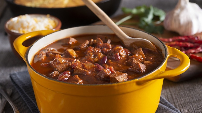 Yellow pot filled with stew with a wooden spoon