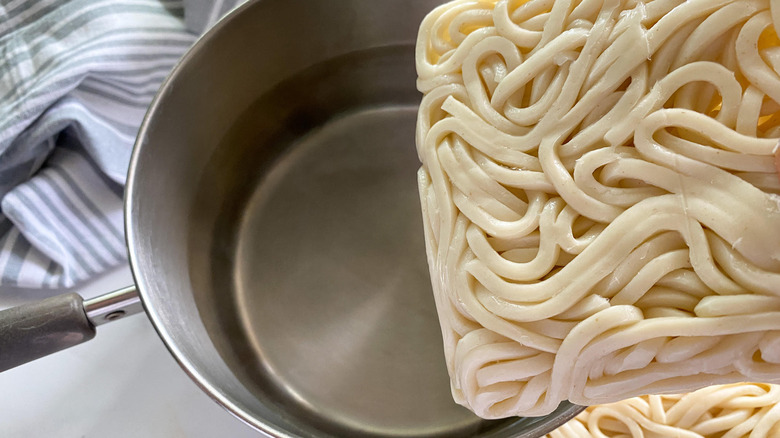 noodles being added to water 