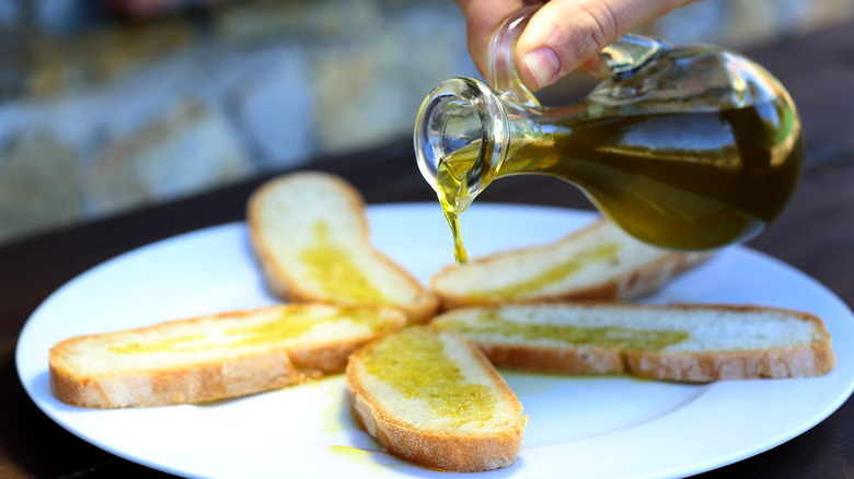 Hand pouring glass vessel of olive oil 