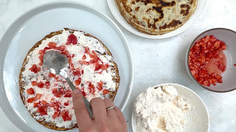 spreading diced strawberries on crepe