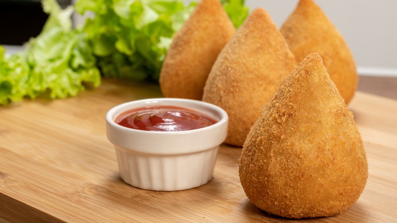 Four coxinhas on wooden board