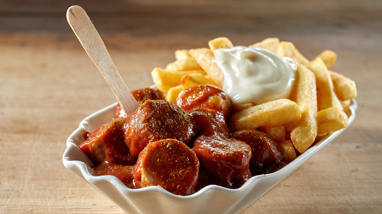 Fluted white dish with currywurst, fries, and mayonnaise