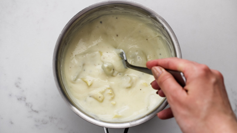 stirring artichoke sauce in pan