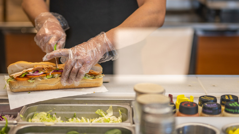 Subway worker cutting sandwich