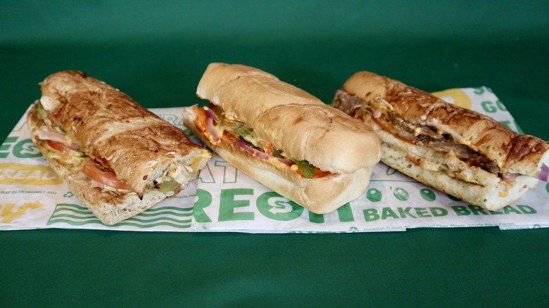 three Subway subs on wrapper green background