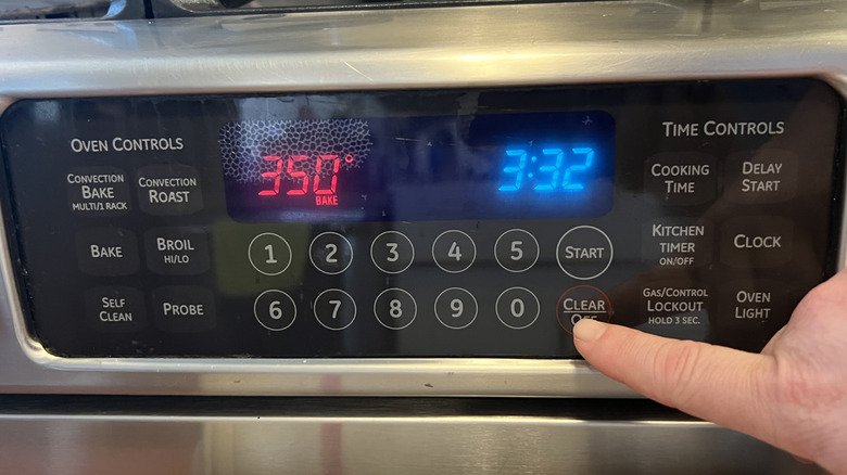 hand touching oven temperature gauge