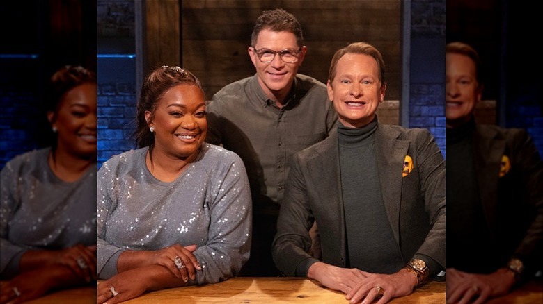 Bobby Flay smiling with Sunny Anderson and Carson Kressley