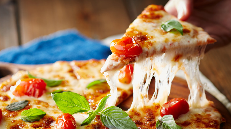 A slice of pizza being pulled from a pie