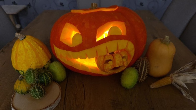 A larger pumpkin carved to look like its eating a smaller one