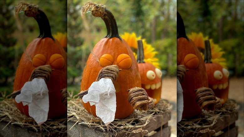 A carved pumpkin holding a tissue