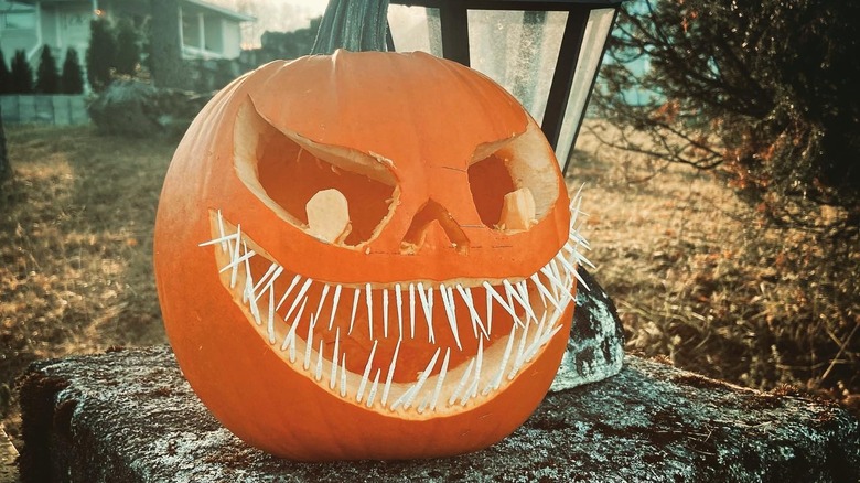 A carved pumpkin with toothpicks for teeth