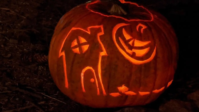 A pumpkin carved with a haunted house and pumpkin moon