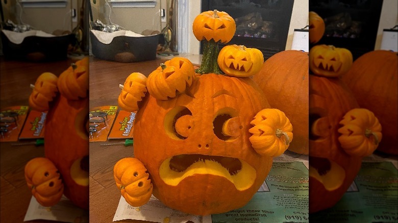 A larger carved pumpkin covered in smaller pumpkins