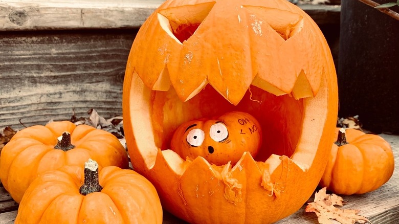 A smaller pumpkin inside the mouth of a jack-o-lantern