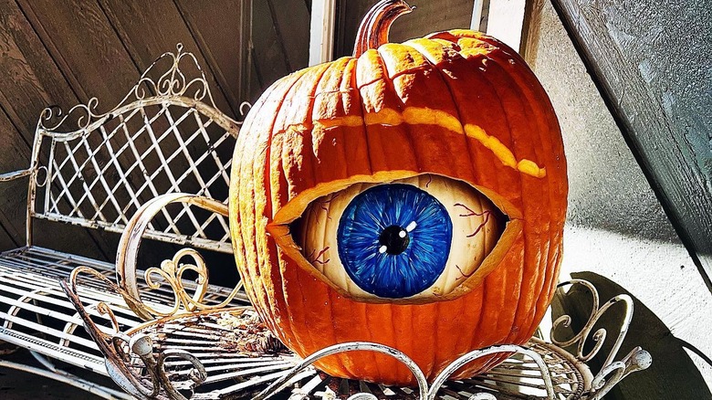 A pumpkin with a painted eye inside a larger pumpkin