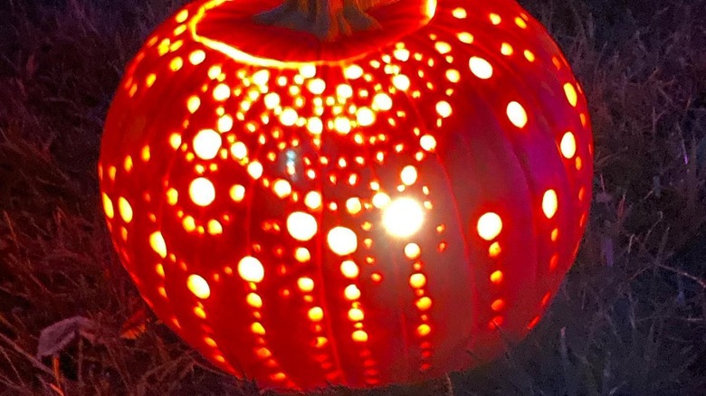 A pumpkin carved with designs made from drilled holes