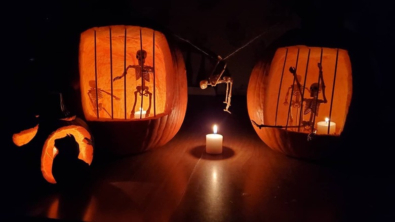 Two pumpkins carved to look like jails with skeletons inside