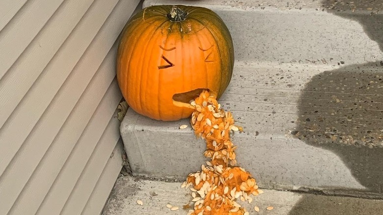 A carved pumpkin spilling seeds and pumpkin innards