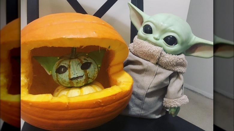 A pumpkin carved to reveal a stack of mini pumpkins shaped like Baby Yoda