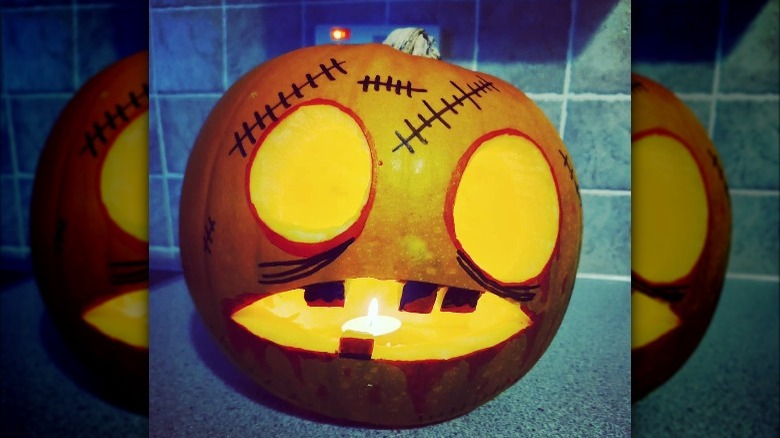 A pumpkin carved to look like a cartoon zombie