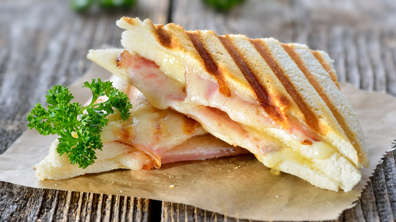 A toasted ham and cheese sandwich cut diagonally on a napkin