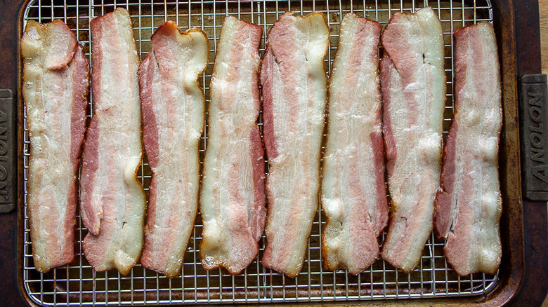 bacon strips that have been par-cooked on a baking sheet