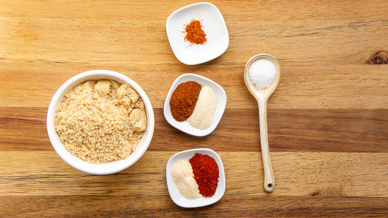 spices and sugar in white bowls with a spoonful of salt