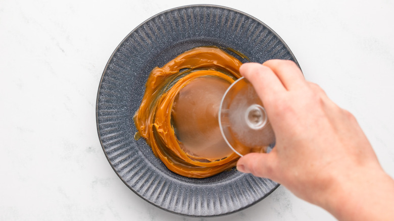 Dipping martini glass rim into caramel sauce