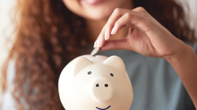 woman putting money into a piggy bank