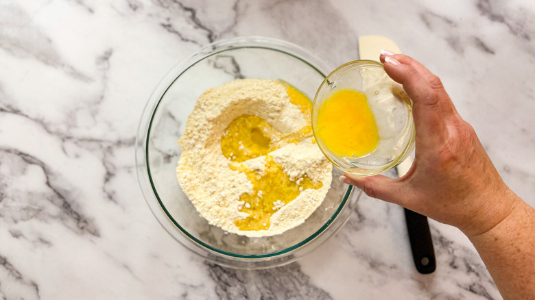 hand pouring eggs into bowl