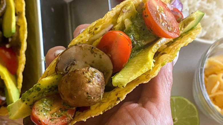 Hard taco shell filled with mushrooms, green sauce, and veggies.