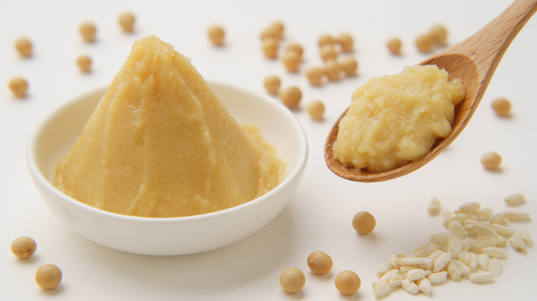 shiro miso paste over white background surrounded by raw soybeans