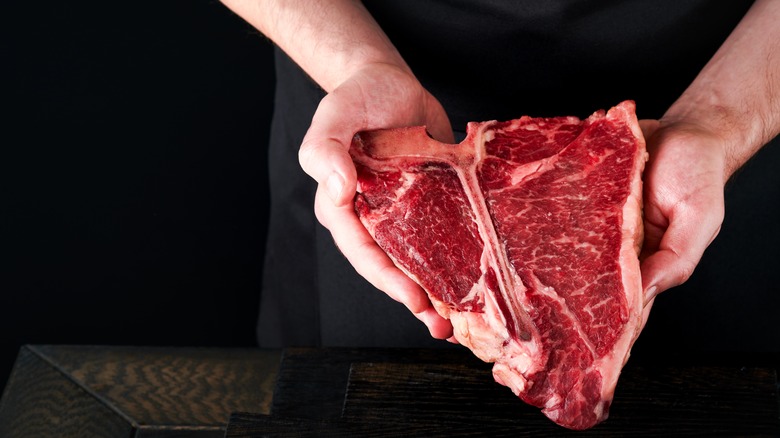 man holding fresh t-bone steak