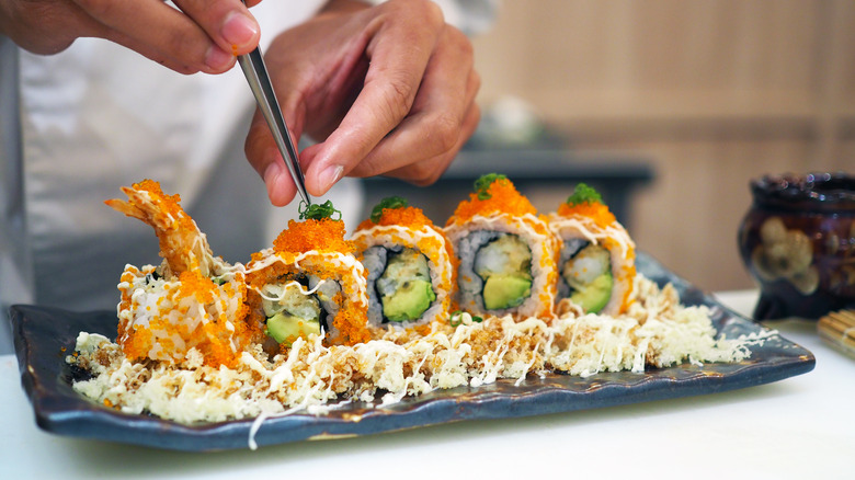 Chef presenting a plate of tempura rolls