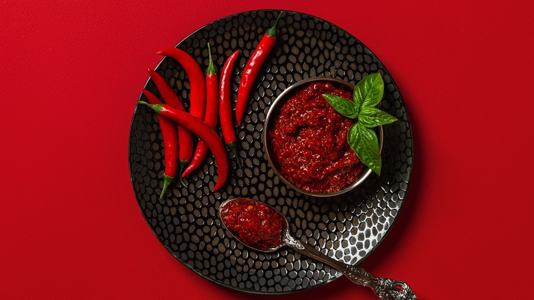 red chili peppers and bowl of hot sauce with spoon