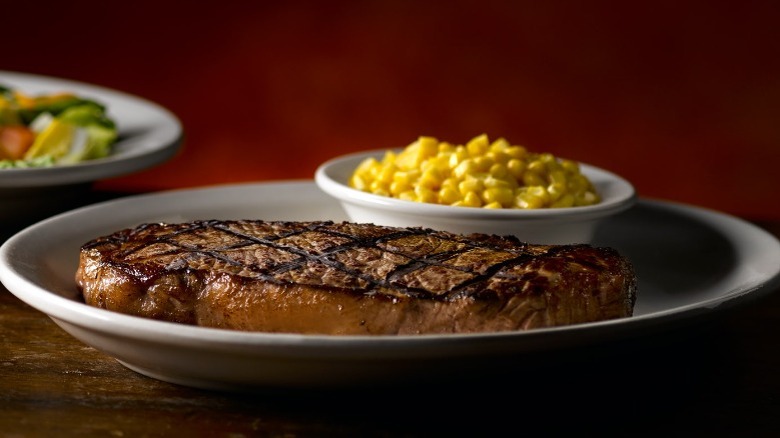 New York strip steak next to a bowl of corn