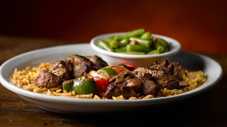 Steak kabobs on a plate with rice and green beans