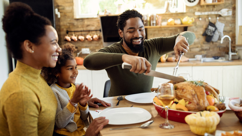 Man and family carving turkey