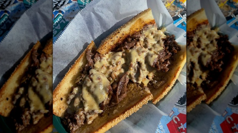 A cheesesteak on garlic bread sits on paper