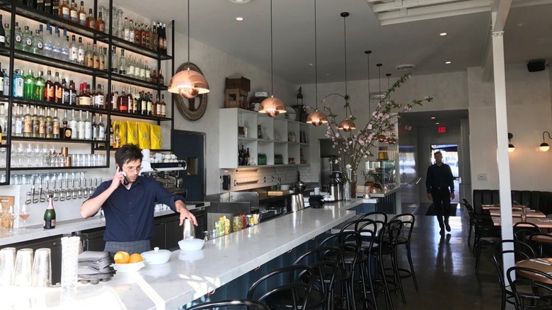 server on phone behind bar 